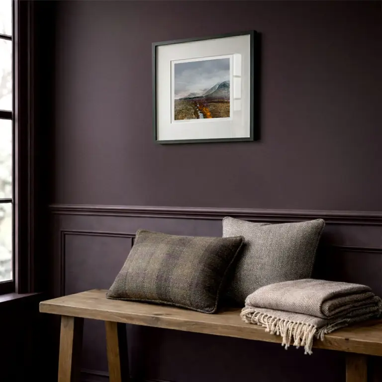 Framed Glencoe print by Scottish artist Carol McEwan. On an aubergine wall with Scottish coorie decor and an antique oak bench with tartan tweed cushions