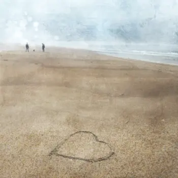 Beach Walk - 2 people in the distance walking their dog no a beach in the rain with a loveheart drawn in the sand