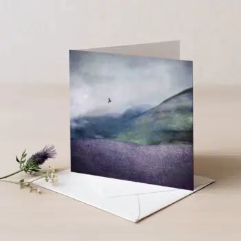 Hills of Tweed greetings card which is an abstract image of a hill in green colours with purple tweed texture on the bottom and a grouse bird flying against a grey dramatic cloudy sky