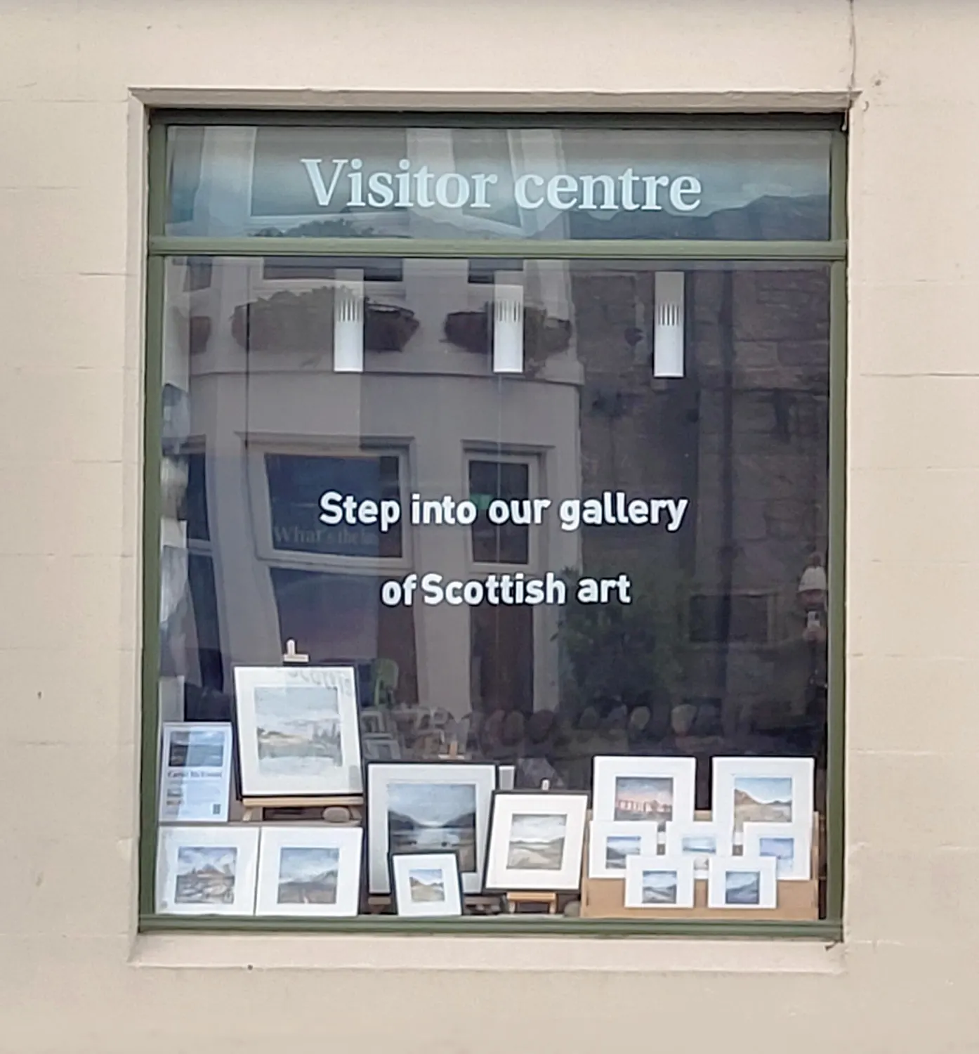 Carol McEwan art prints in shop window of Scottish visitor centre. window decal says "Step into our gallery of Scottish Art"